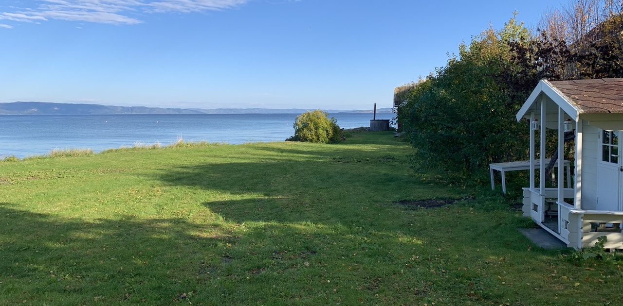 Sjøutsikt m/strandlinje, hage, naust