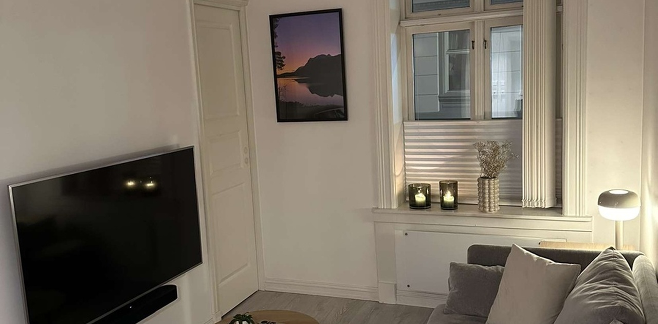 Stue med tvoppheng. En skyvedør inn til soverommet på hver side av tven