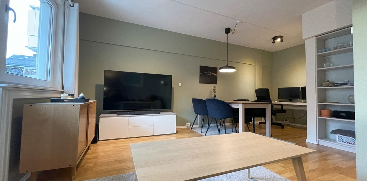 Den romslige stuen er innredet med sofakrok, spisebord med stoler, TV og kontorpult