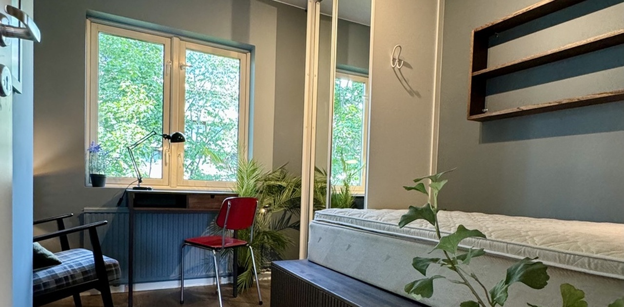 Meget pent og praktisk rom med innbygger seng med flere lagringsløsninger under. Speil skyvedørsgsrderobe med hyller, skuffer og garderobestang. Solid, fastmontert skrivebor. Lesenisje med lenestol. To møbelsnekrede hyller, over sengen og over lenestolen.