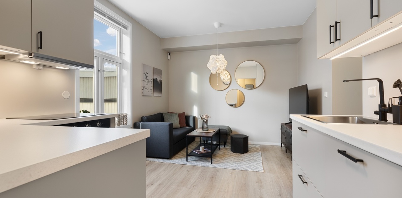Lys og moderne stue med åpen kjøkkenløsning. Fullt møblert med komfortabel sofa, stuebord og TV.