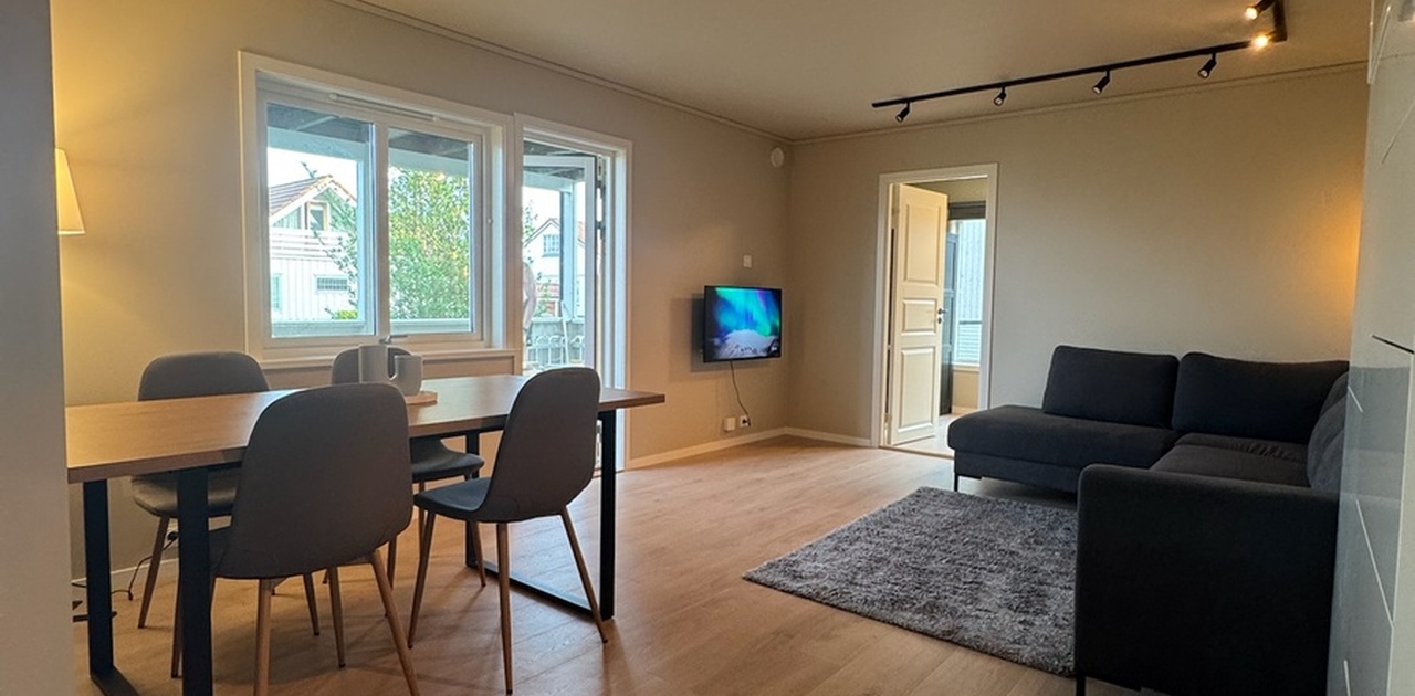 Romslig og lys stue med spisebord, sofa og TV