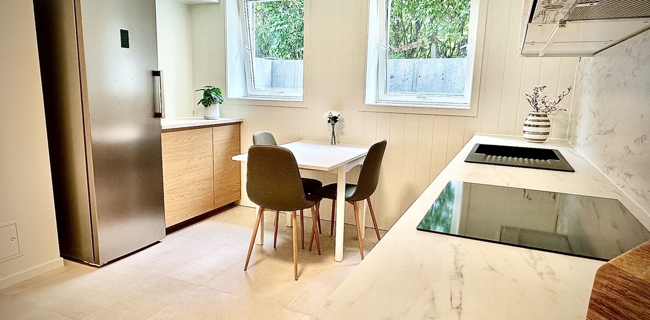 Nytt kjøkken med integrerte hvitevarer, kjøkkenbord og stoler. Alt nytt og ubrukt.