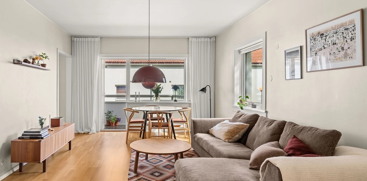Hyggelig stue med spisebord, sofagruppe og peis.