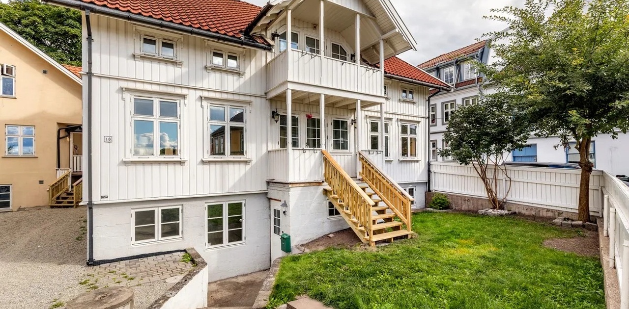 Gammelt bilde av huset fra framsiden. Det er nå installert platting som dekker hele gressplenen.
