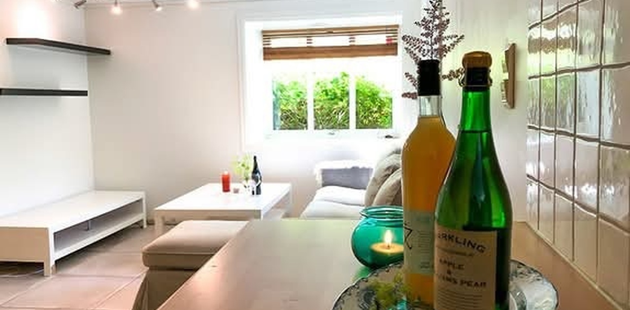 Utsikt fra kjøkken mot stue og to store vinduer ut mot skjermet hage