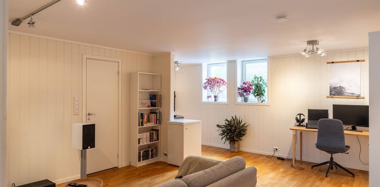 Stor stue/spisestue med parkett, gulvvarme, malte lyse flater, store vinduer og gode lysforhold.