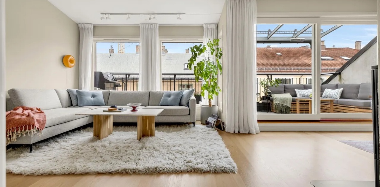 Stue med stor sofa, tv og utgang til terasse