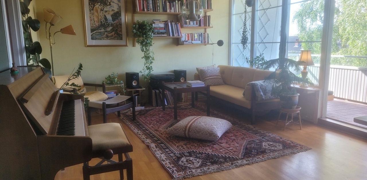 Stor stue med sittegruppe, piano, stort spisebord og med utgang til balkong.