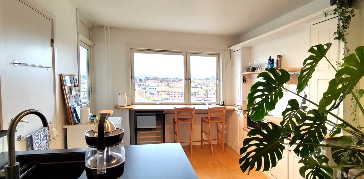 Åpen kjøkkenløsning med spiseplass foran vinduene.