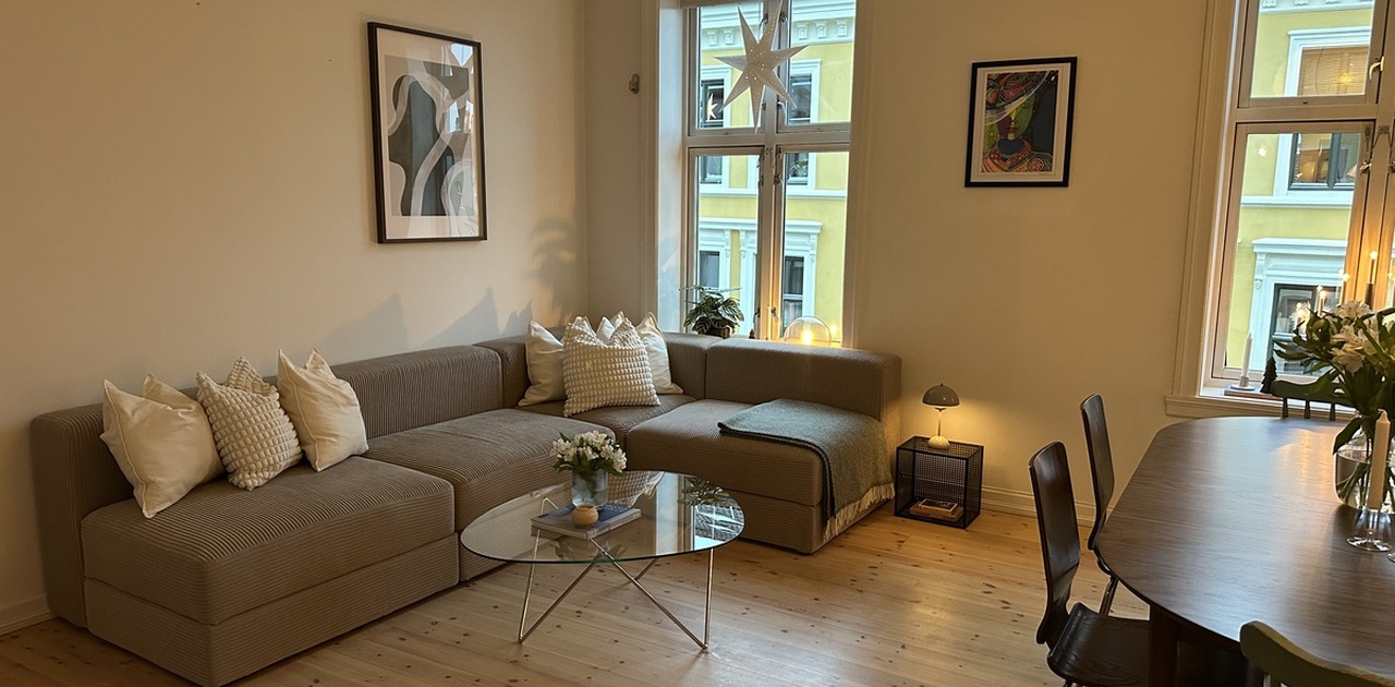 Romslig og hyggelig stue med stor sofa og langbord