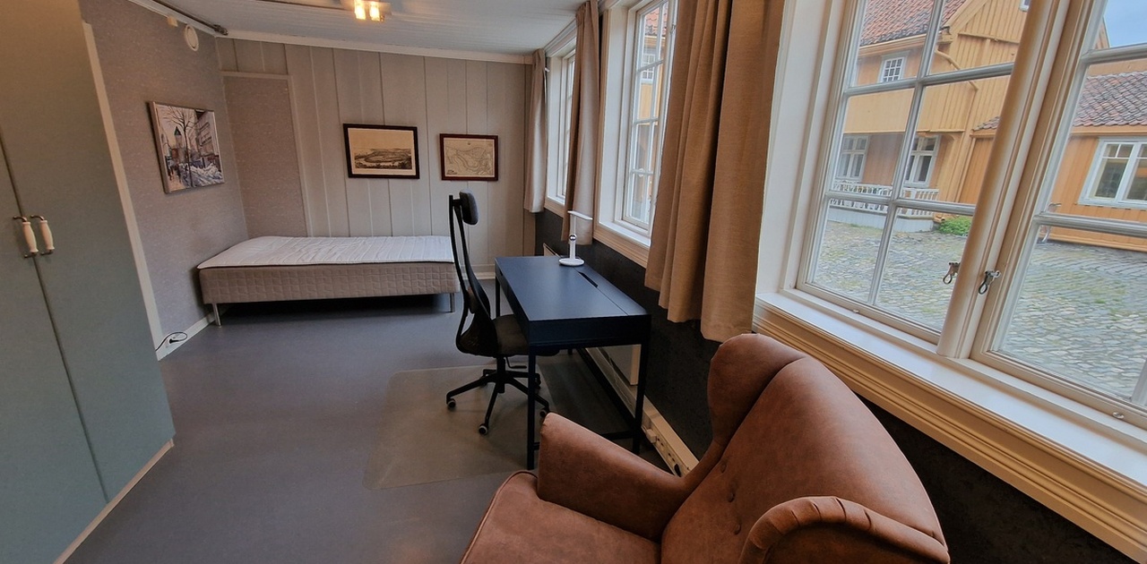 Rommet er lyst med store vindu inn mot pent gårdsrom i fredet anlegg.