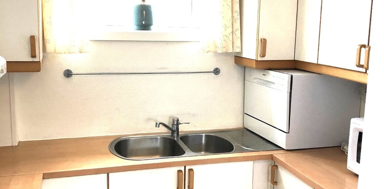 Fin og romslig kjøkkenkrok med induksjonstopp, oppvaskmaskin og microovn