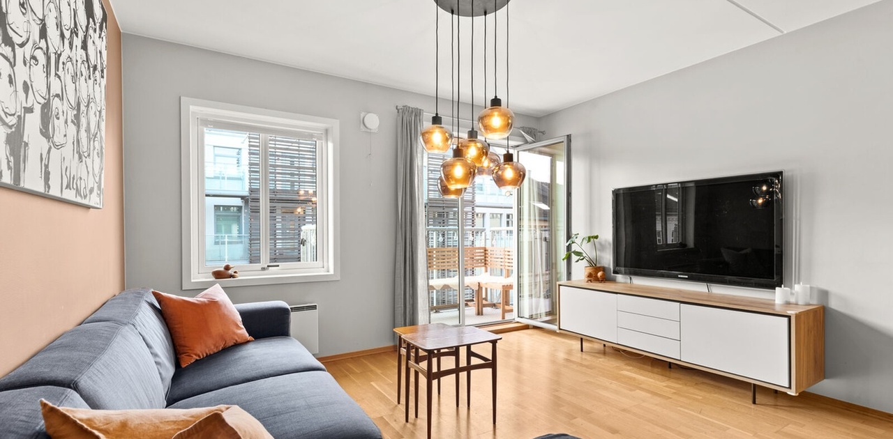 Stue med sofa og tv, dør til balking. NB: møblene på bildet er utdaterte.