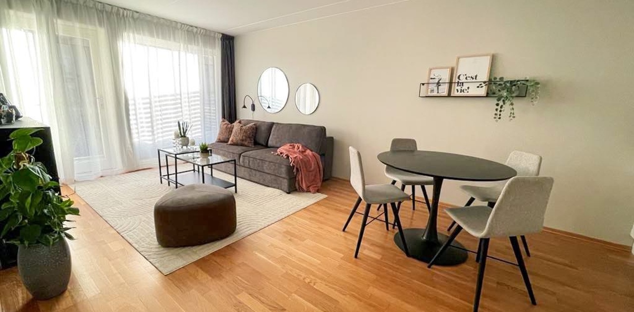 Lys stue med store vinduer fra gulv til tak. Det er også liftgardiner spesialtilpasset i vinduene i tillegg til gardiner fra gulv til tak.