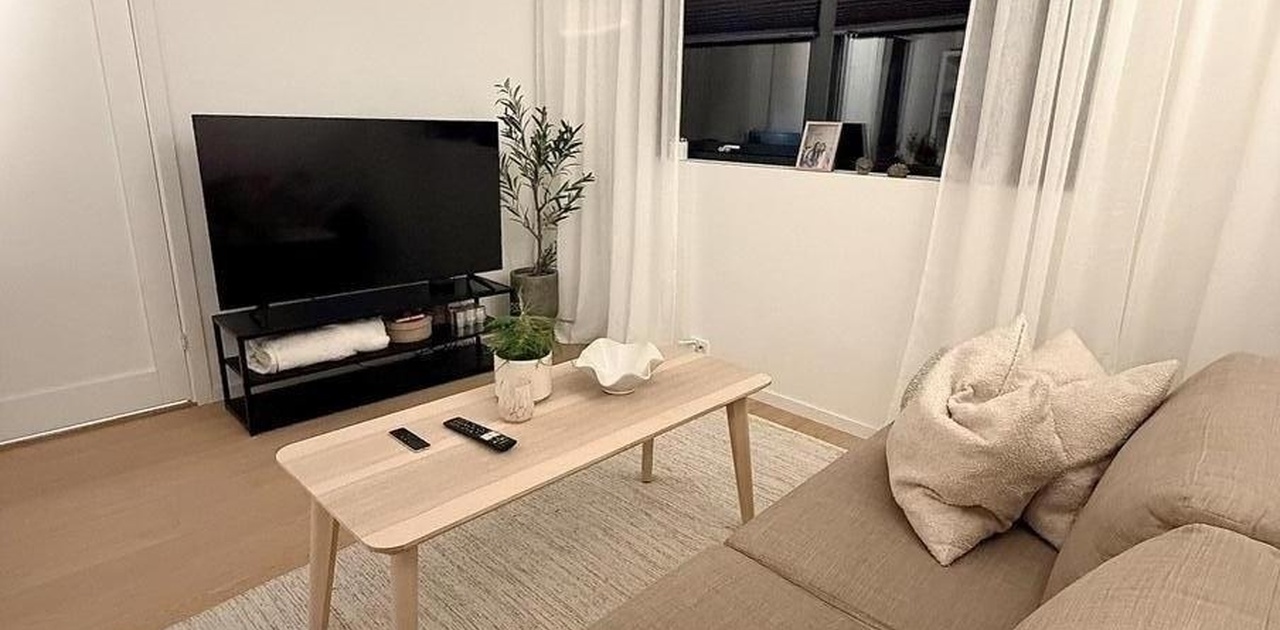 Lys og moderne stue med koselig sitteområde og store vinduer.