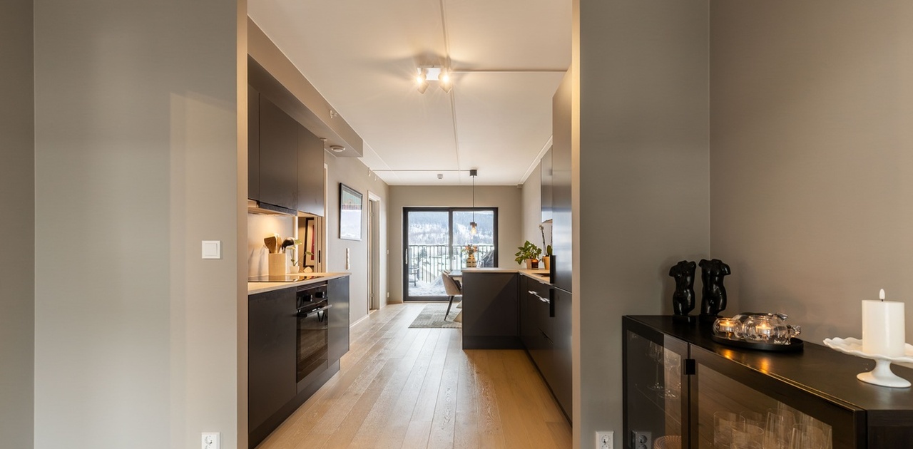 Kjøkken med øyløsning deler stue naturlig i en spisestuesone og en sone med tv/sofa