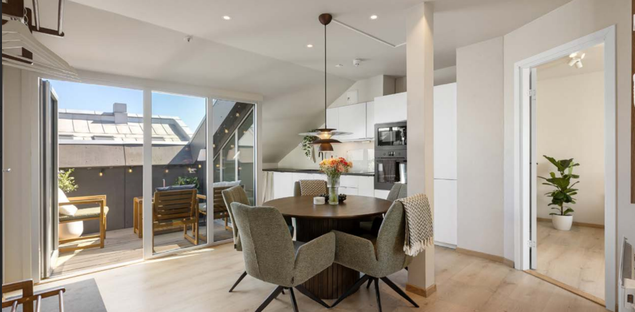 Lys og romslig stue med åpen kjøkkenløsning og direkte utgang til solrik balkong