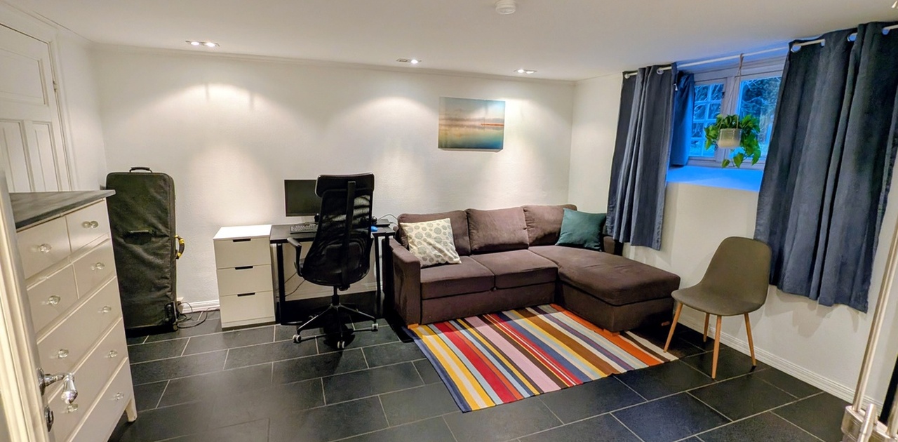 omslig kombinert sove- og oppholdsrom med kontorplass og stor sovesofa.