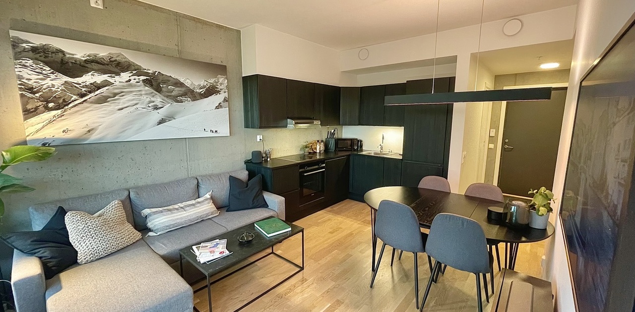 Hjørnekjøkken med god skapplass, induksjonstopp, mikrobølgeovn, airfryer, stekeovn, oppvaskmaskin, kjøleskap og fryser.