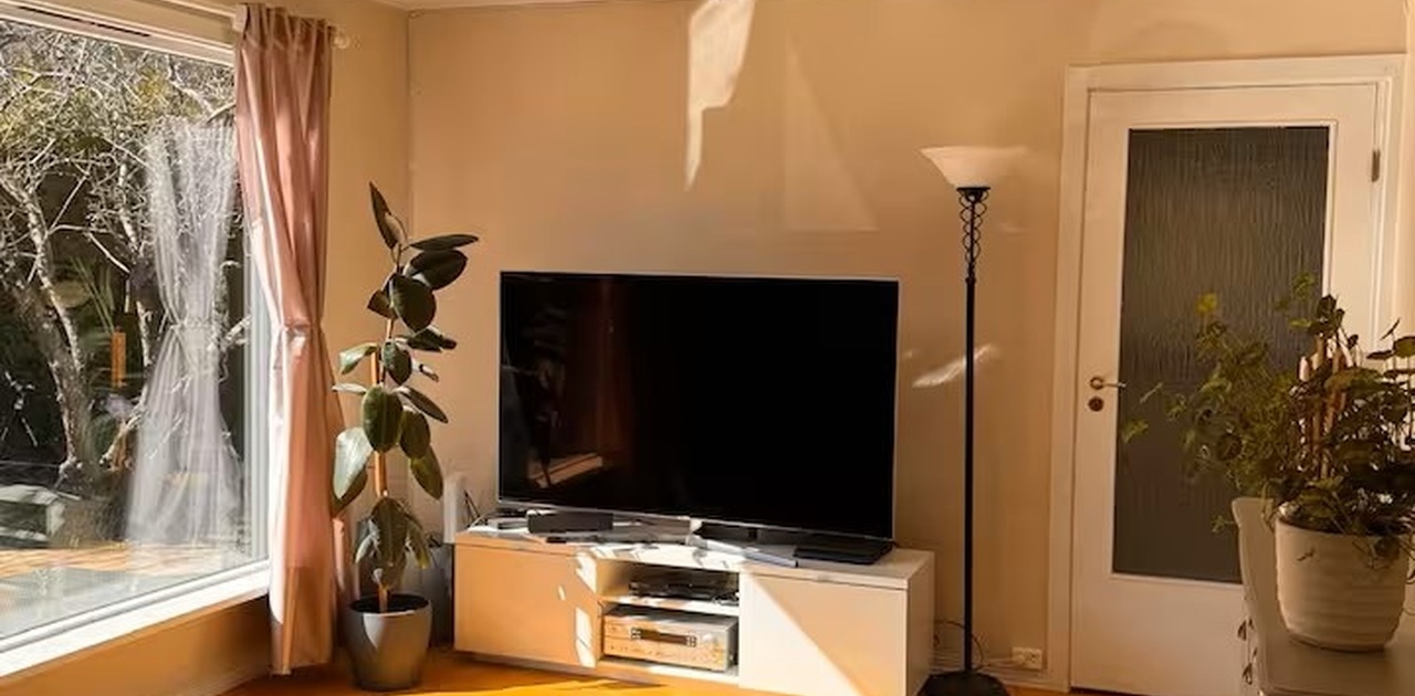 Lys stue med stor TV, parkett og direkte tilgang til inngang