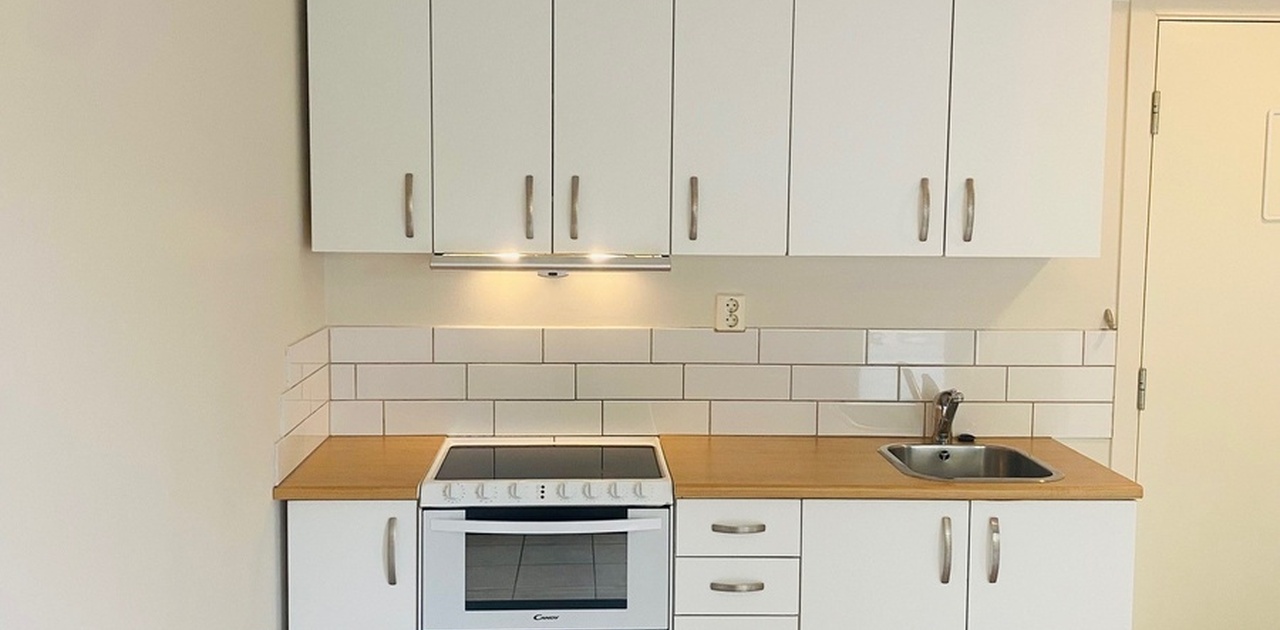 Kjøkkeninnredning med kombinert stekeovn,oppvaskmaskin og platetopp.