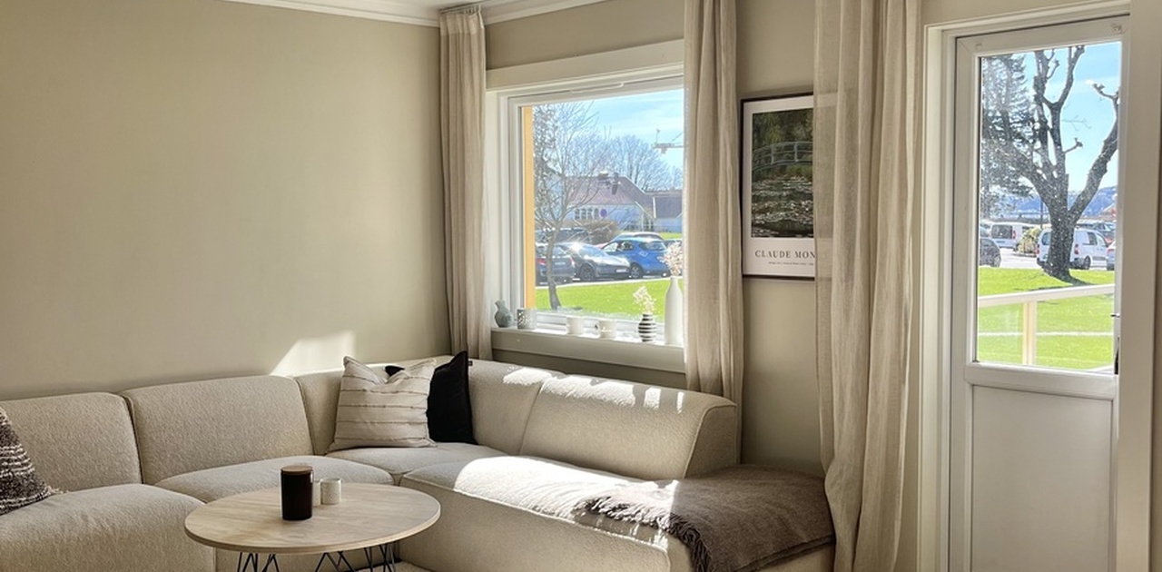 Store vinduer i stua som gir mye lys. Her ser du også dør ut til balkongen.