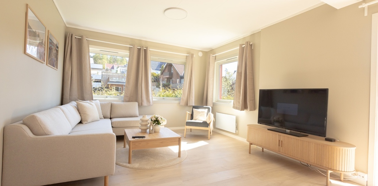 Flott og stor stue med flere vinduer som gir mye lys