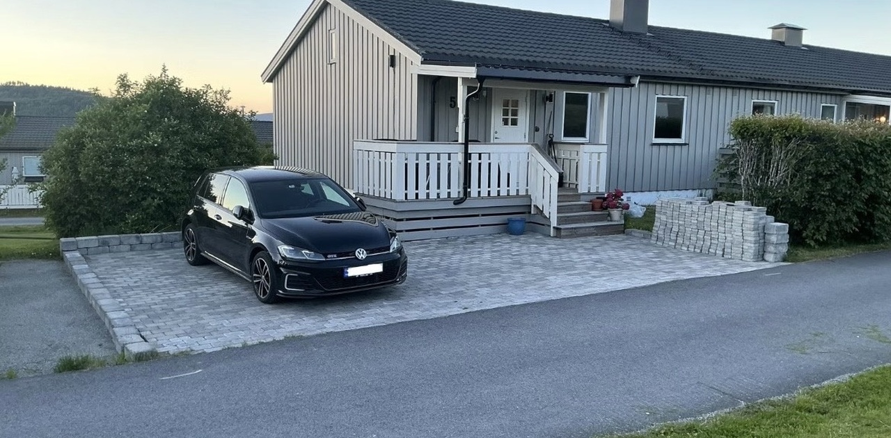 Parkeringsplass foran rekkehuset. Det er i tillegg garasjeplass med installert el-billader. Den ekstra belegningssteinen flyttes ila sommeren.