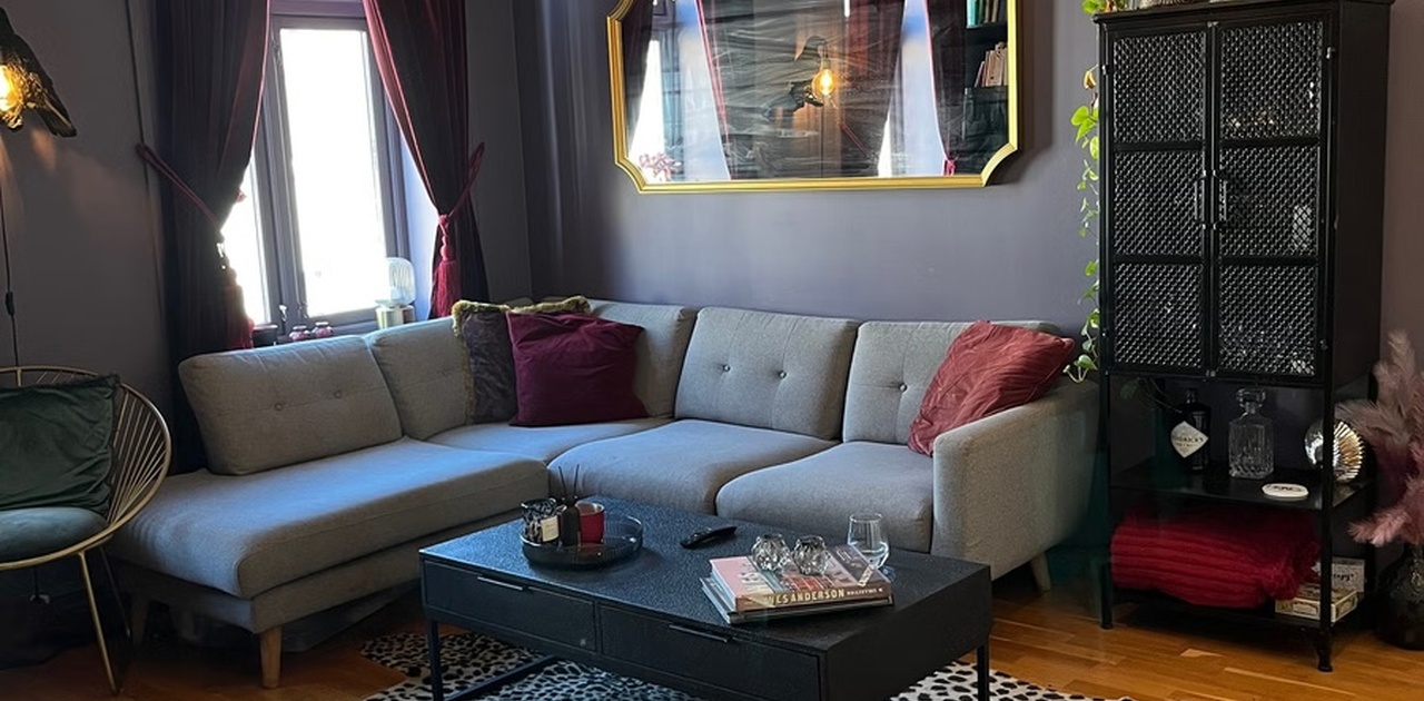 Stor romslig stue med plass til sofa, skap og annet. Åpen kjøkkenløsning og TV installert.