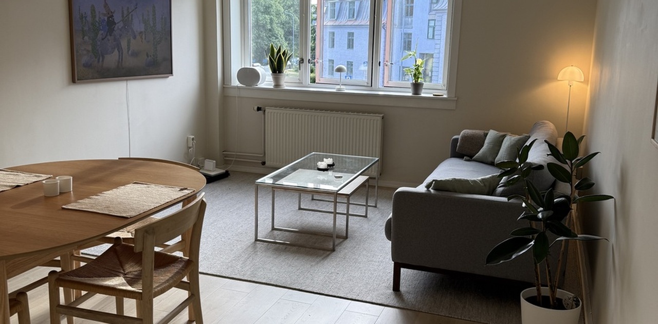Lys og romslig stue med store vinduer, hyggelig sitteplass og god plass til både spisebord og sofakrok.