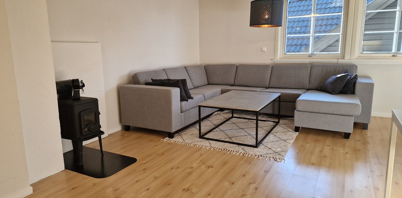 Lys og møblert stue med sofagruppe, spiseplass og god plass til opphold.