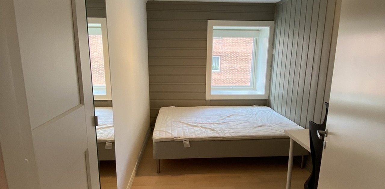 Soverom med både skap, seng og skrivebord