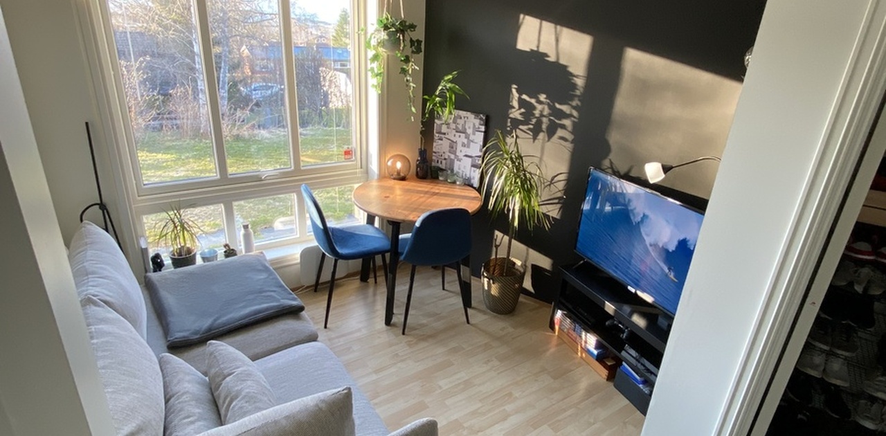 Lys stue med store vinduer ut mot hage.