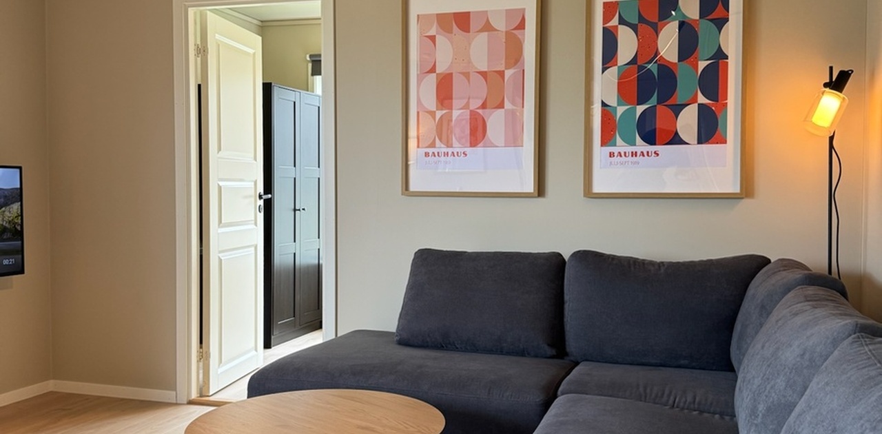 Romslig og lys stue med spisebord, sofa og TV