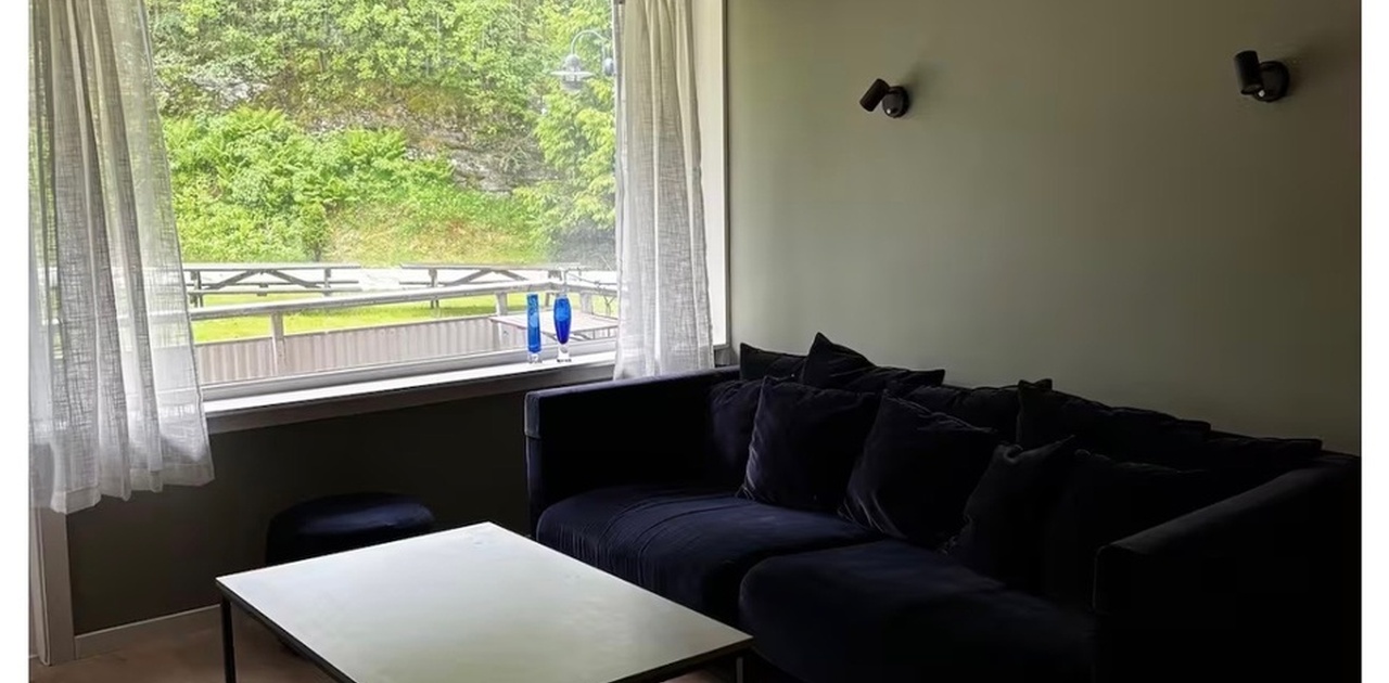 Lys fin stue med utgang til liten balkong, og utsyn mot felle hage.