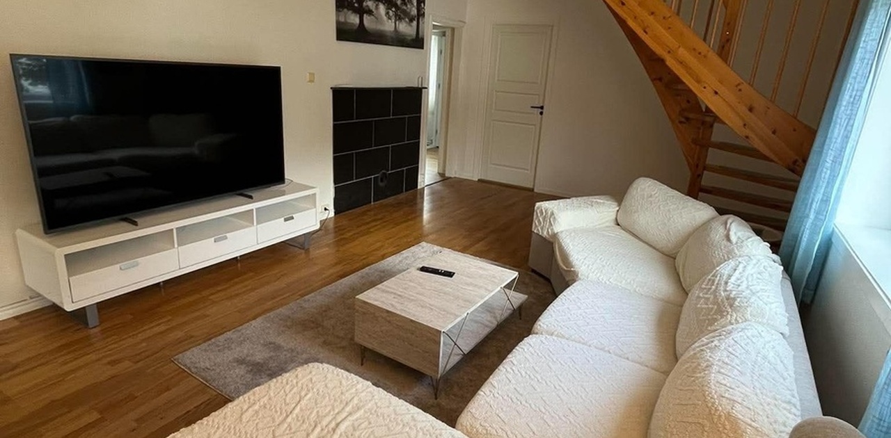 Romslig og hyggelig stue med sofa, stuebord, TV-benk og 70" TV