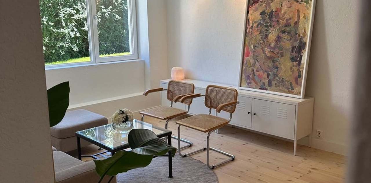 Lys og romslig stue med store vindusflater og utsikt til privat uteplass.