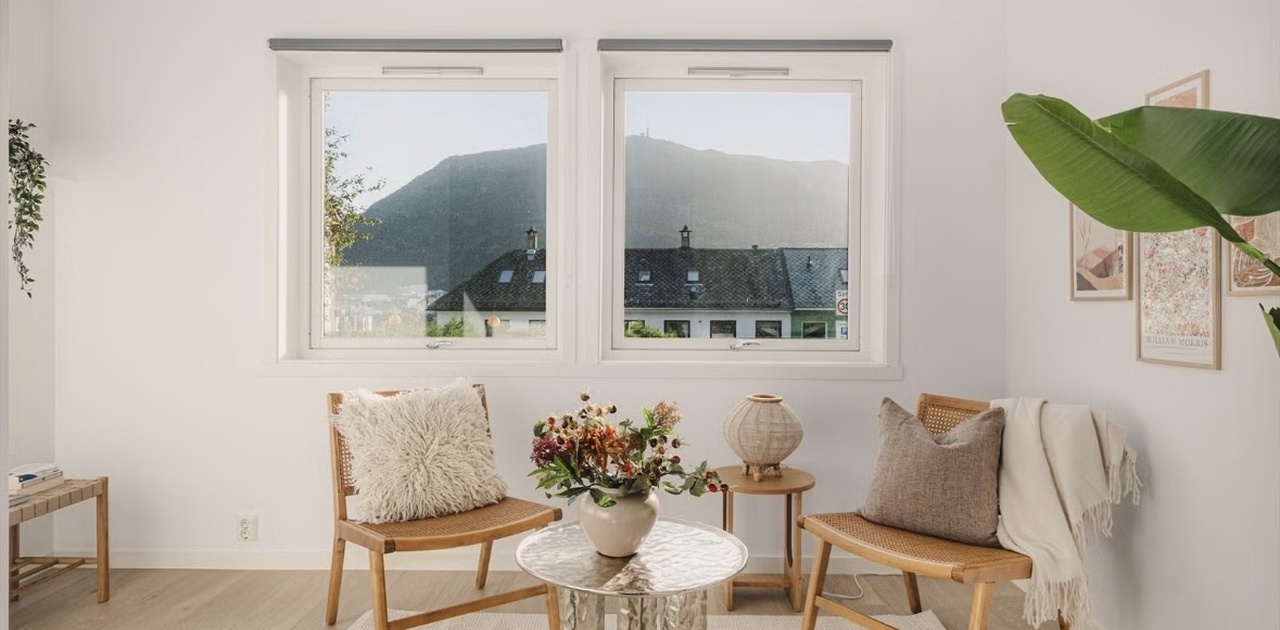 Store vinduer rammer inn en flott utsikt mot fjellene og fyller oppholdsrommet med dagslys.