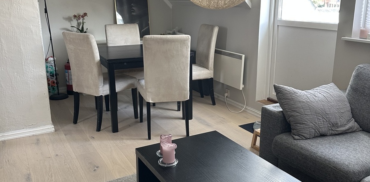 Stuen byr på lyst tregulv, en trivelig spiseplass under skråtaket og en stor, flettet taklampe som blikkfang.