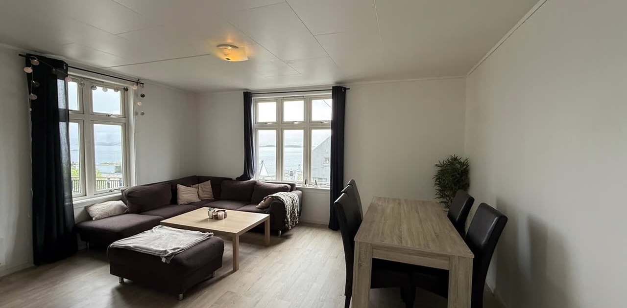 Stuen er innredet med en stor hjørnesofa og spiseplass, og har store vinduer som gir utsyn mot sjøen.
