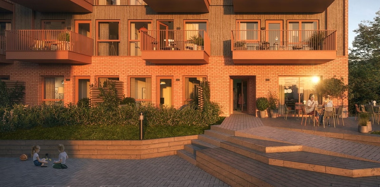 Fasaden i varmt kveldslys har et opparbeidet utområde med sitteplasser og private balkonger/terrasser