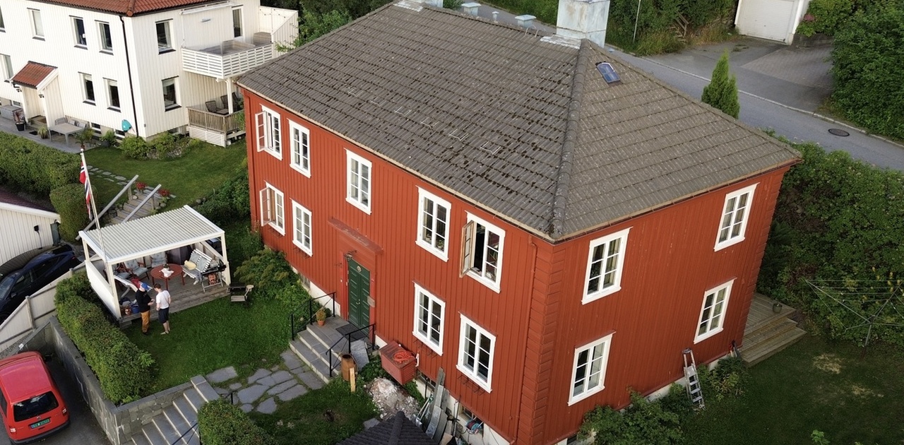 Det karakteristiske røde trehuset ligger omkranset av en grønn hage, med uteplass og parkering. Svært nære til mange kollektivruter.