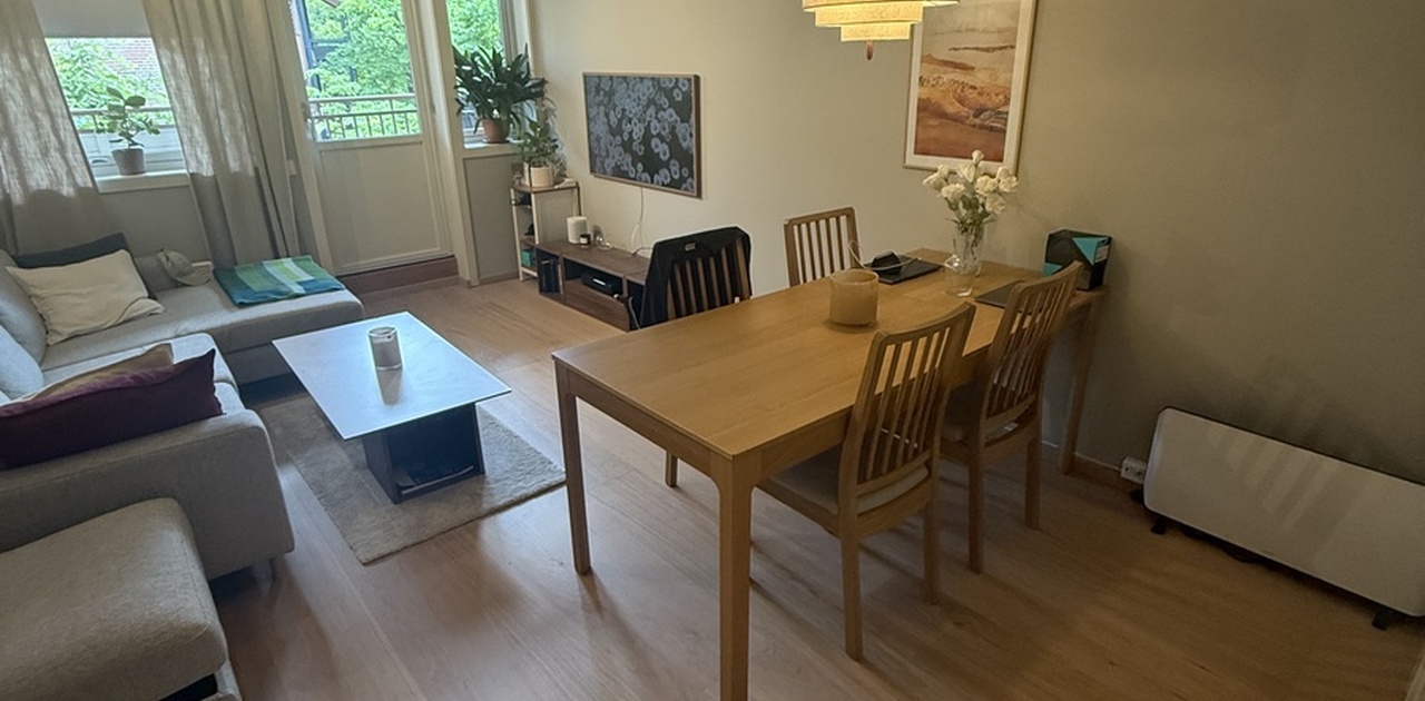 Stuen har lys eikeparkett og plass til både spisebord og sofaavdeling, med direkte utgang til balkong.