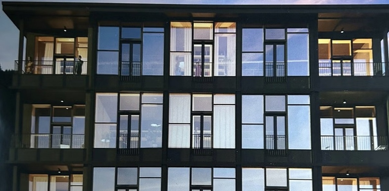 En moderne bygningsfasade med store glassflater og integrerte balkonger.