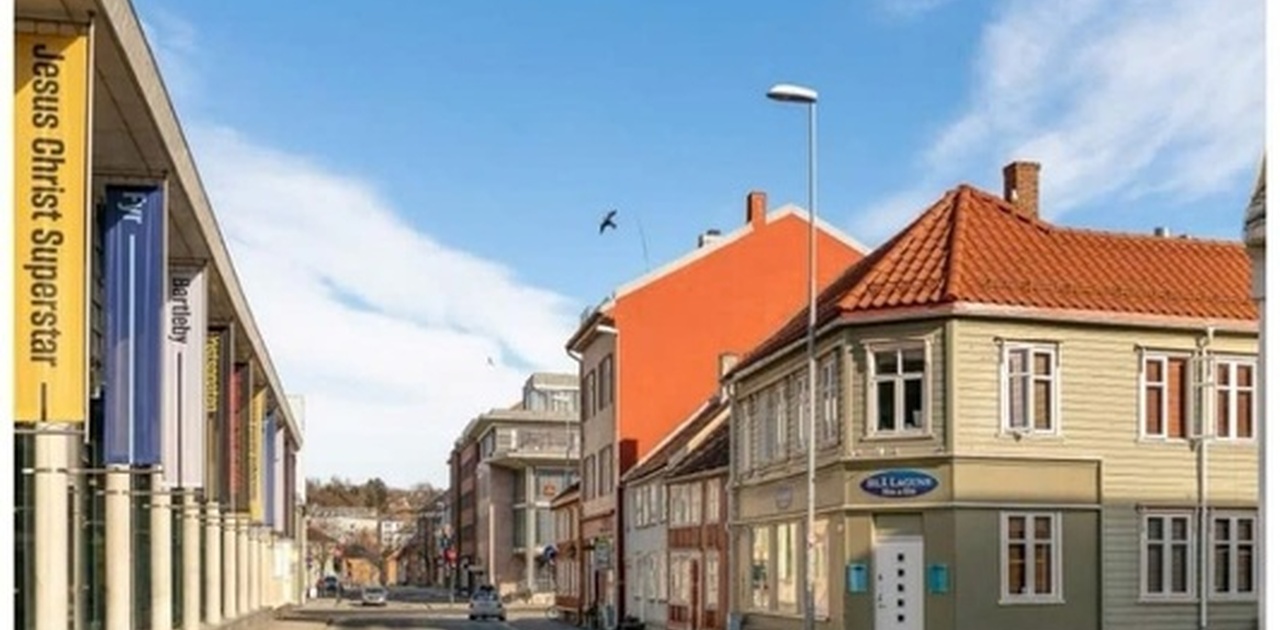 Bygningen har klassisk trepanel og ligger i et sentralt bymiljø like ved et moderne kulturbygg.