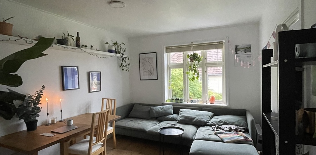 Stuen er innredet med en romslig vinkelsofa plassert under vinduet og et spisebord.