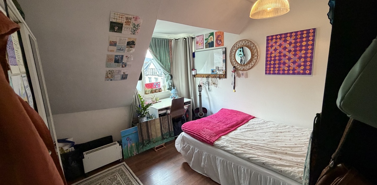 Soverommet i loftsetasjen har skråtak og en lys vindusnisje innredet med skrivebord.