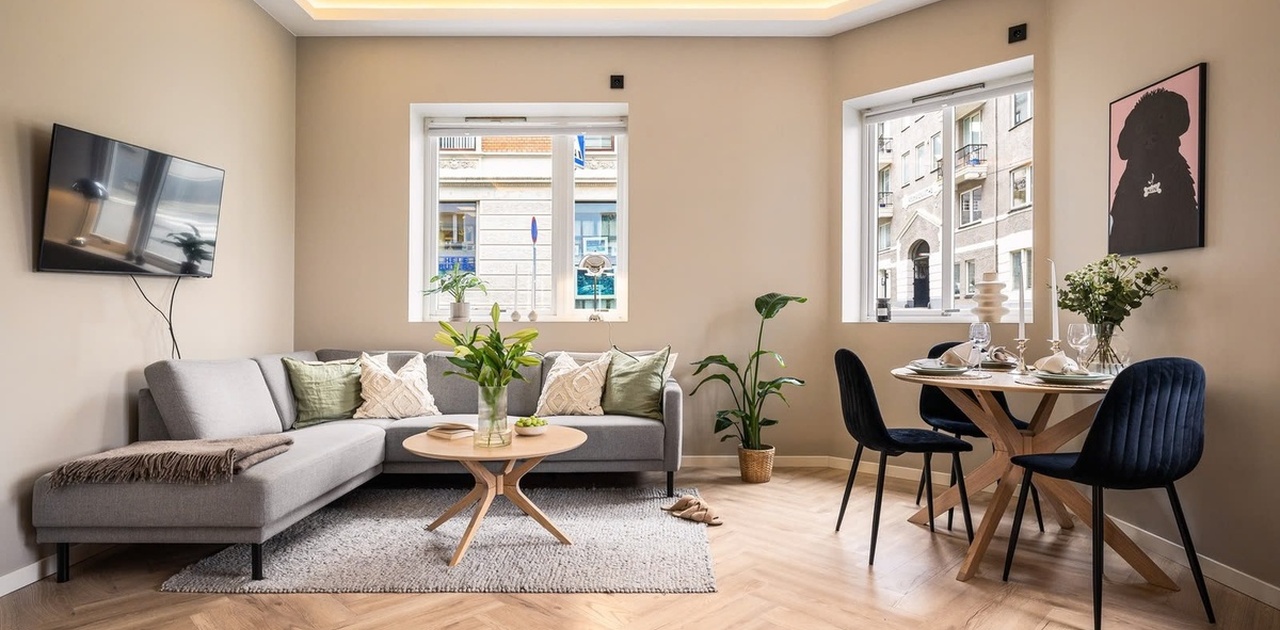 Fiskebeinsparkett og nedfelt LED-belysning i taket gir stuen et elegant uttrykk, innredet med både grå hjørnesofa og spiseplass.