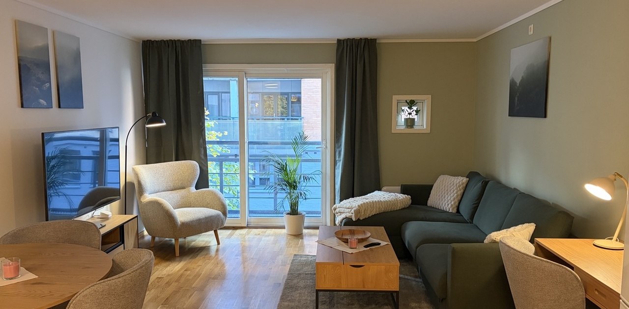 Stuen sovesofa 140x200 cm, skrivebord og utgang til balkong gjennom store skyvedører i glass.